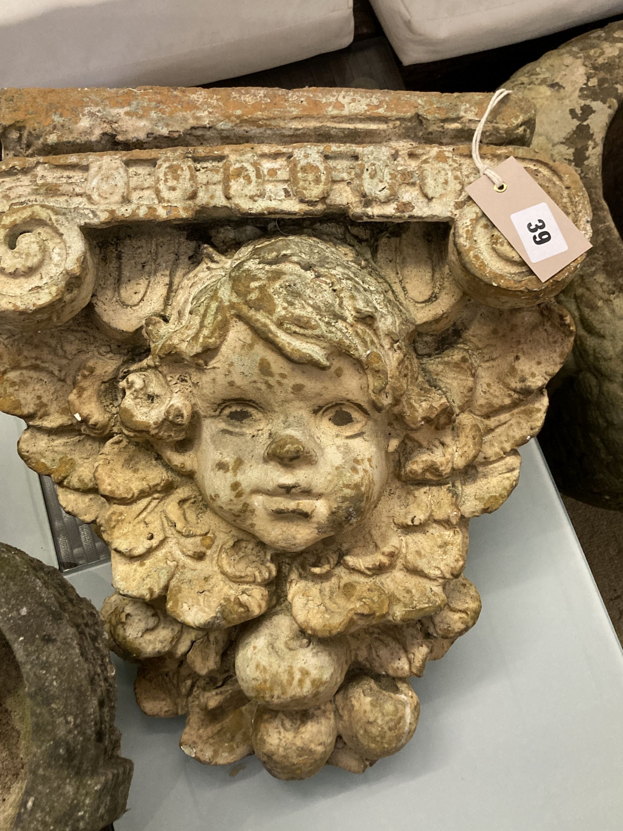 A terracotta pigs head wall applique, height 28cm, a composition bracket and a stone urn